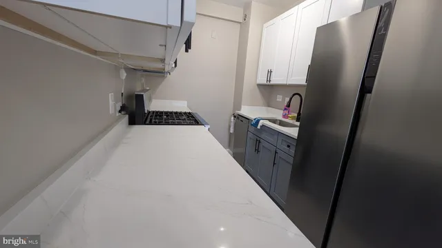 a view of a kitchen with refrigerator and white cabinets