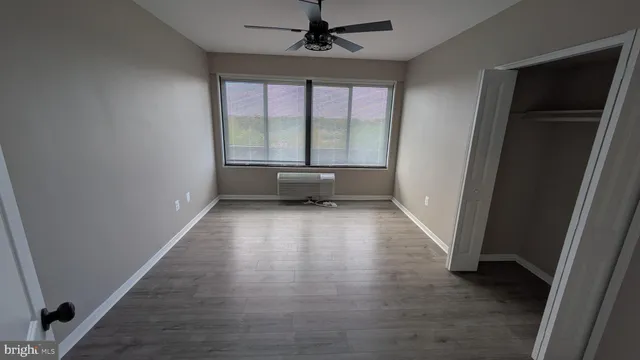 an empty room with wooden floor fan and windows