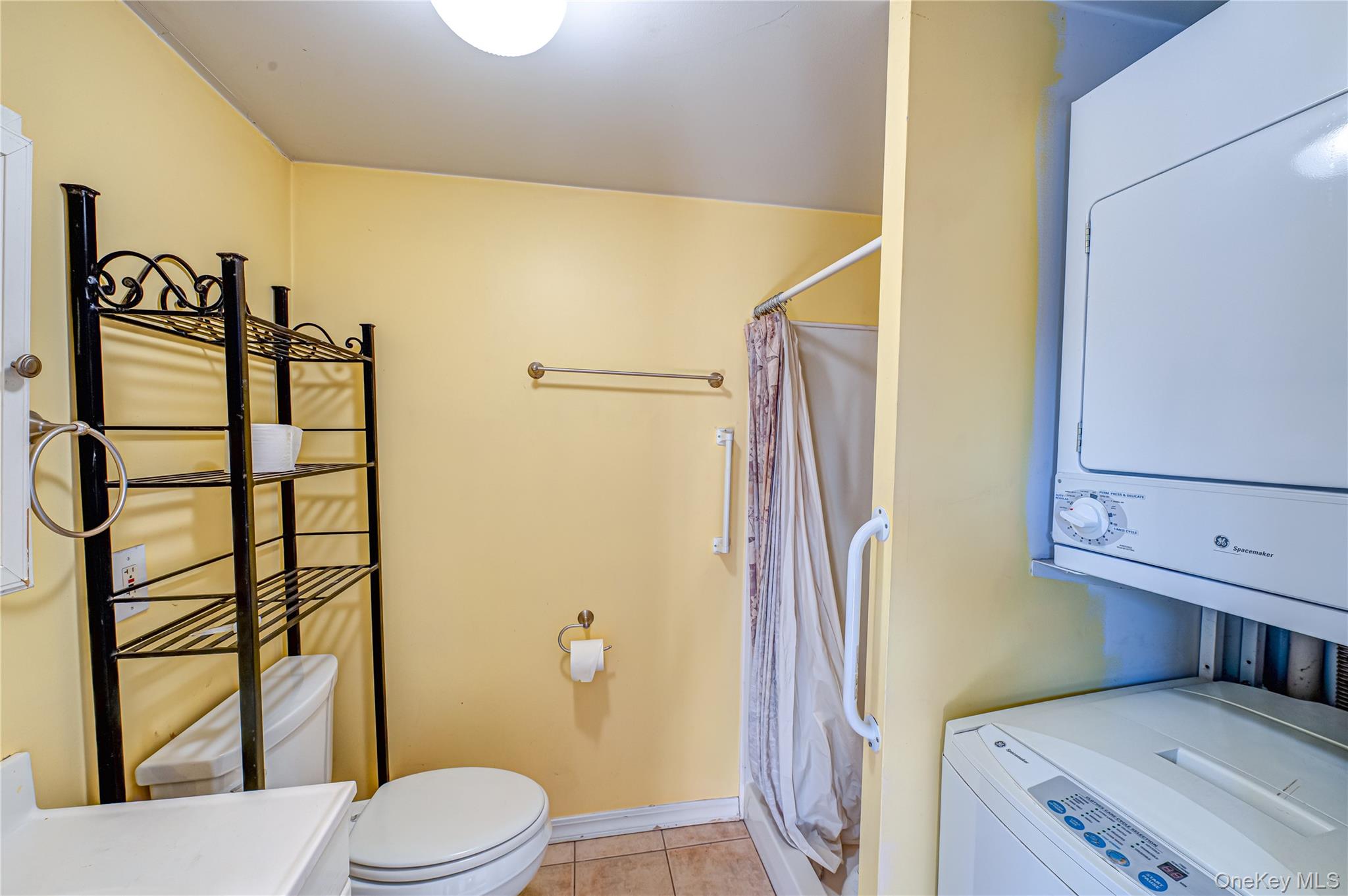 179 G Springville Road Hampton Bays, NY 11946 - Photo 29 of 45 Bathroom with curtained shower, light tile patterned floors, stacked washing machine and dryer, and vanity