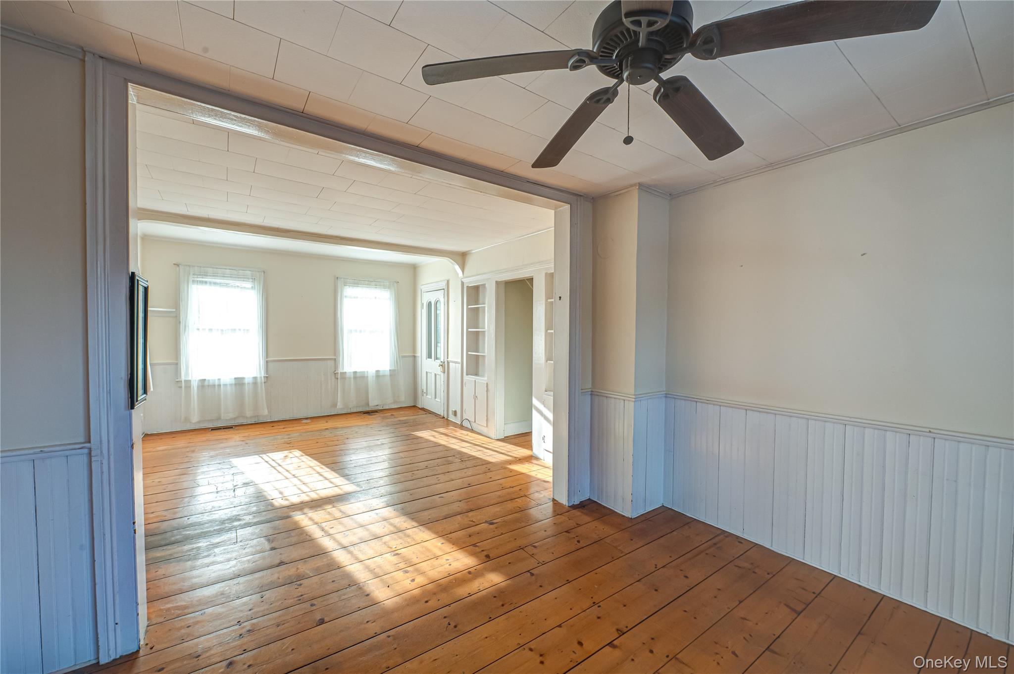 179 G Springville Road Hampton Bays, NY 11946 - Photo 6 of 45 Spare room featuring wainscoting, light wood-style flooring, and a ceiling fan