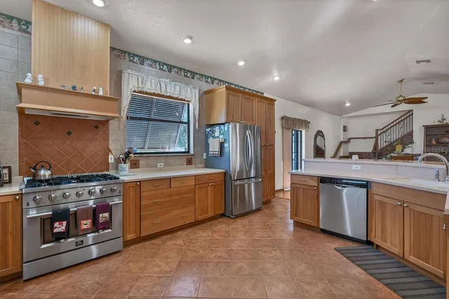 a kitchen with stainless steel appliances granite countertop a stove a sink and a refrigerator