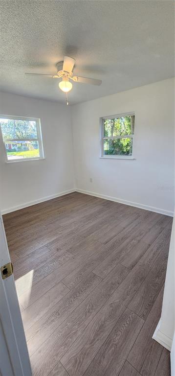 390 Clark Street Deltona, FL 32725 - Photo 8 of 10 an empty room with wooden floor chandelier fan and windows