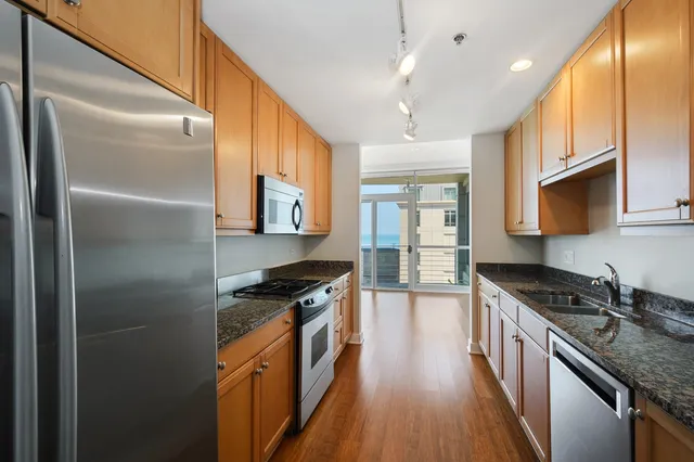 a kitchen with stainless steel appliances granite countertop a stove a sink and a refrigerator