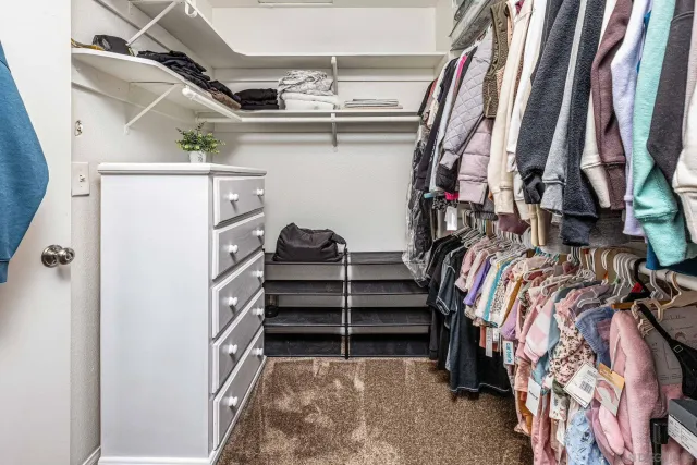 a view of walk in closet with clothes and shoes