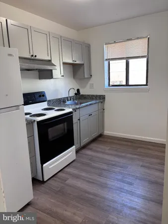 a kitchen with granite countertop wooden floors and white stainless steel appliances