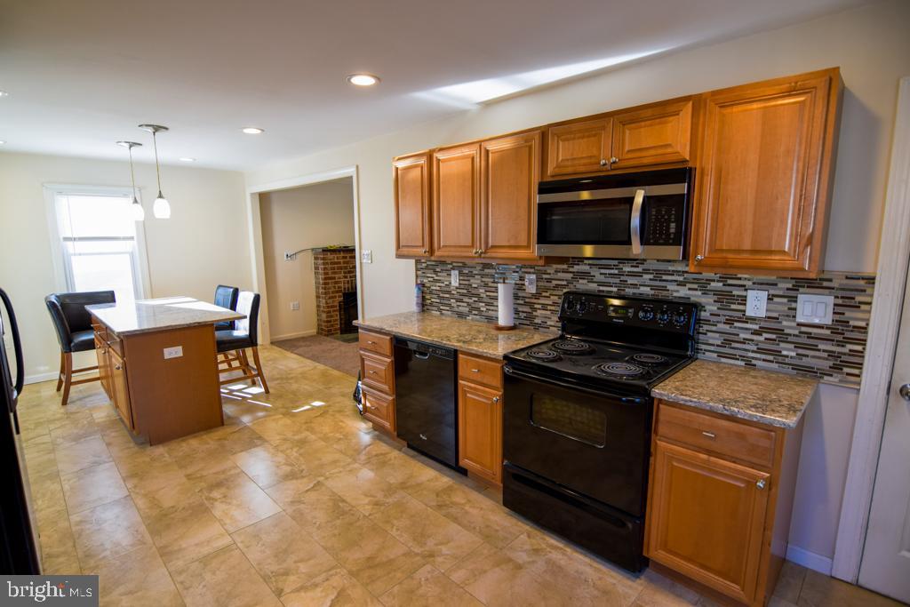 1071 West Bristol Road Warminster, PA 18974 - Photo 4 of 34 a kitchen with stainless steel appliances granite countertop a stove top oven a sink dishwasher a dining table and chairs with wooden floor