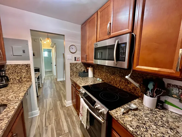 a kitchen with granite countertop stainless steel appliances a stove sink and cabinets