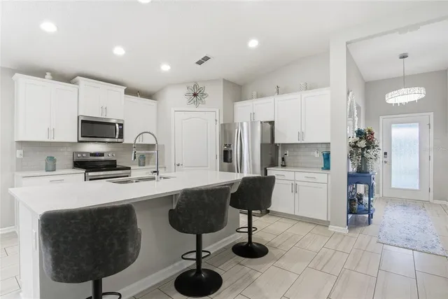 a kitchen with stainless steel appliances a refrigerator sink and white cabinets