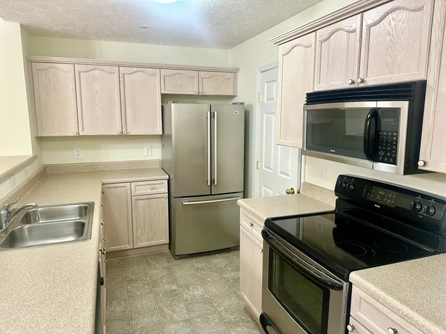 a kitchen with granite countertop a refrigerator stove and microwave