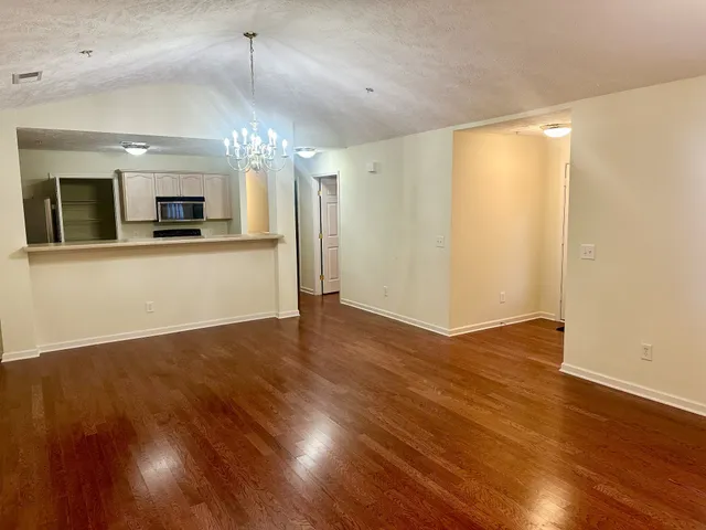 a view of a room with wooden floor ceiling fan and kitchen space