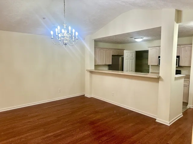 a view of a hallway with chandelier and wooden floor