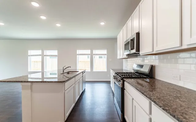 a kitchen with granite countertop a sink a counter space appliances and cabinets