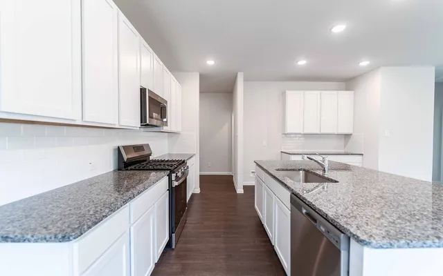 a kitchen with stainless steel appliances granite countertop a sink stove and cabinets