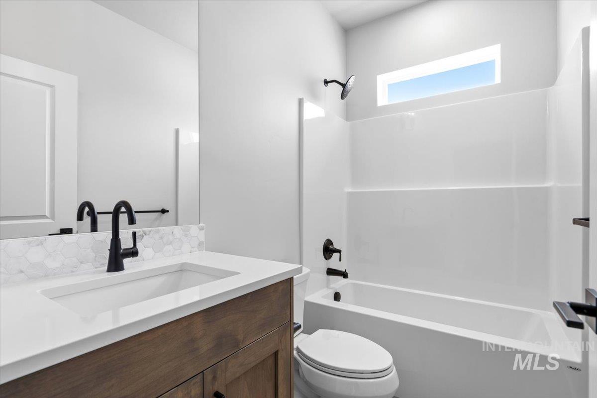 4317 Tropic Way Caldwell, ID 83607 - Photo 28 of 47 Bathroom featuring a wood-finish vanity with an integrated sink, white countertop, and hexagonal tile backsplash