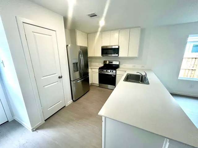 a kitchen with a refrigerator a stove a microwave a sink and cabinets