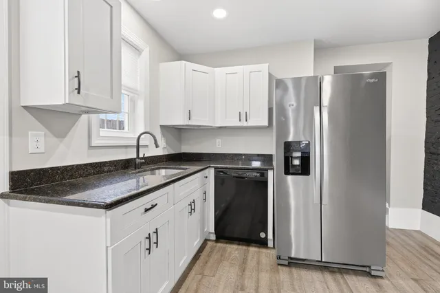 a kitchen with granite countertop a refrigerator sink and cabinets