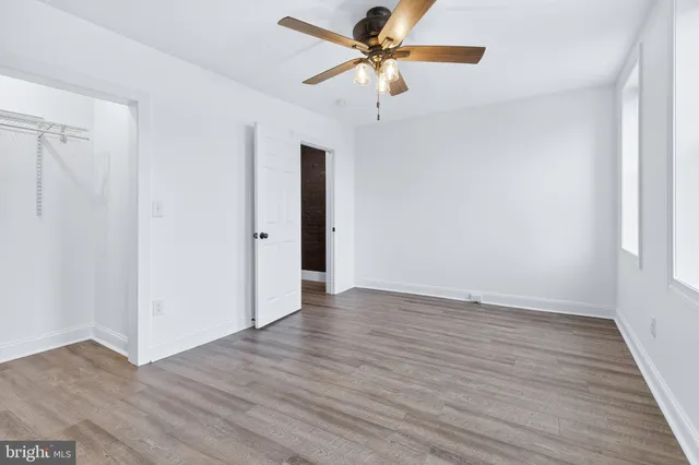 an empty room with wooden floor fan and windows