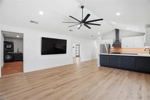 a living room with stainless steel appliances furniture and a wooden floor