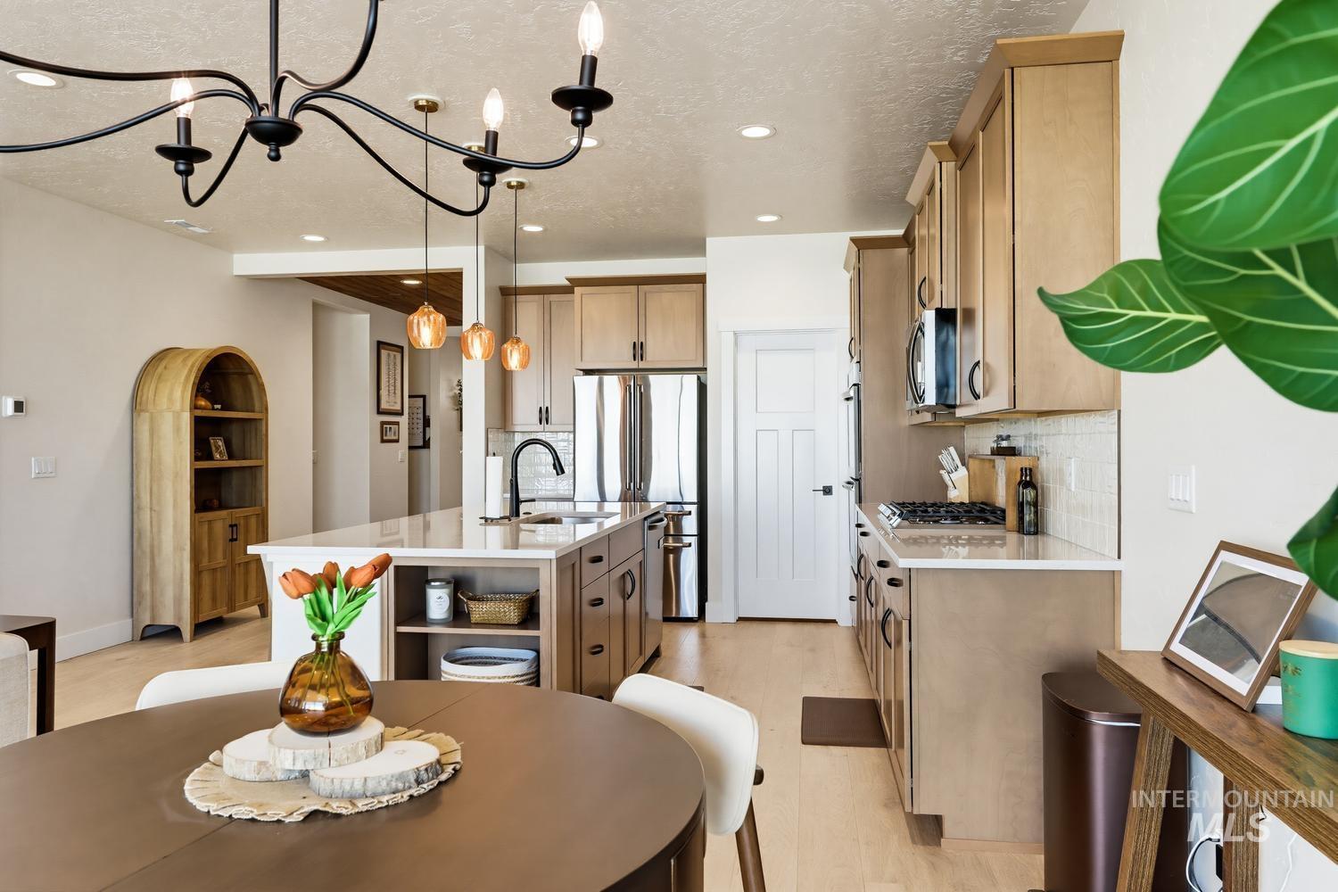 5990 West Ladle Rpds Street Meridian, ID 83646 - Photo 19 of 42 Open-concept kitchen with light wood-finish cabinetry, stainless steel appliances, and a central island with countertop seating