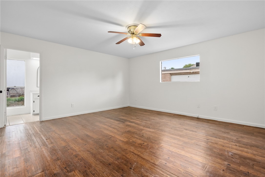5009 Wingfoot Lane, Unit B Corpus Christi, TX 78413 - Photo 13 of 23 an empty room with wooden floor fan and windows