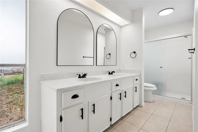 an empty room with wooden floor chandelier fan and windows