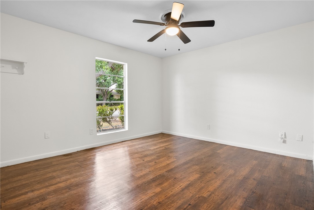 5009 Wingfoot Lane, Unit B Corpus Christi, TX 78413 - Photo 16 of 23 an empty room with wooden floor chandelier fan and windows