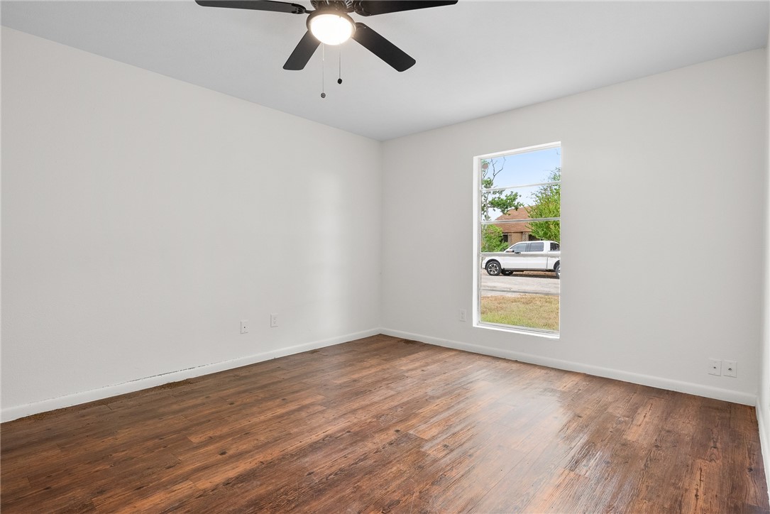5009 Wingfoot Lane, Unit B Corpus Christi, TX 78413 - Photo 18 of 23 an empty room with wooden floor fan and windows
