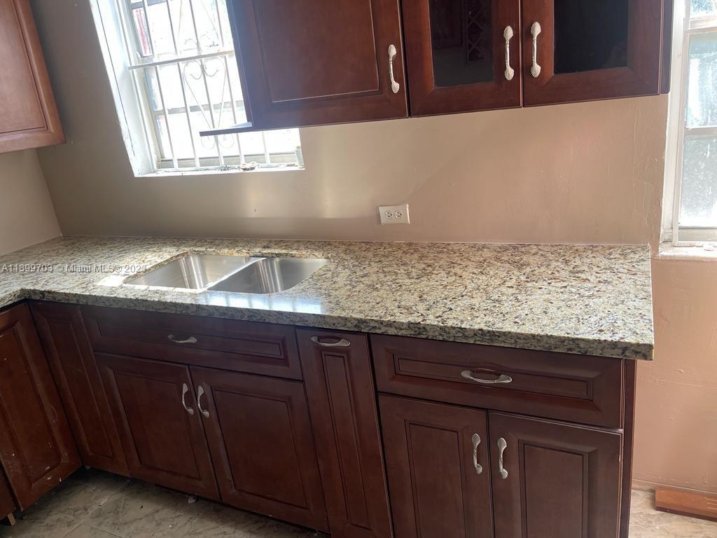 121 Northwest 53rd Street Miami, FL 33127 - Photo 4 of 5 a sink with granite countertop cabinets and window