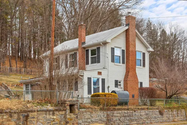 a view of a white house with a large tree and yard