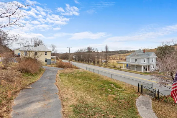 a view of a white house next to a yard with large trees