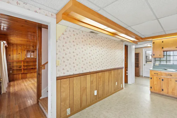 a view of a hallway with wooden floor and a kitchen
