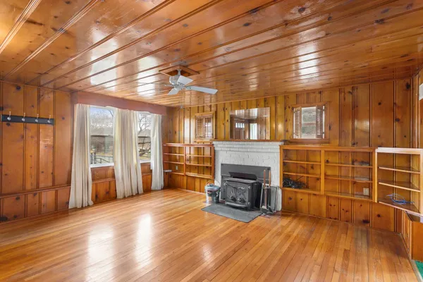 an empty room with wooden floor fireplace and windows