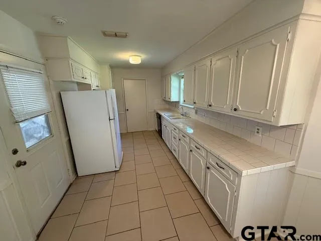 a kitchen with granite countertop a refrigerator a sink and dishwasher