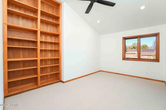 a spacious bedroom with a bed a ceiling fan and a rug