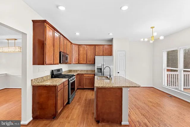 a large kitchen with stainless steel appliances granite countertop a sink stove and wooden floor