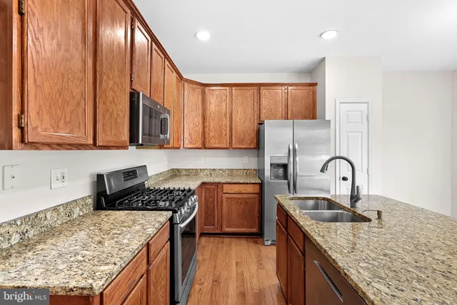 a kitchen with kitchen island granite countertop a sink a counter space appliances and cabinets