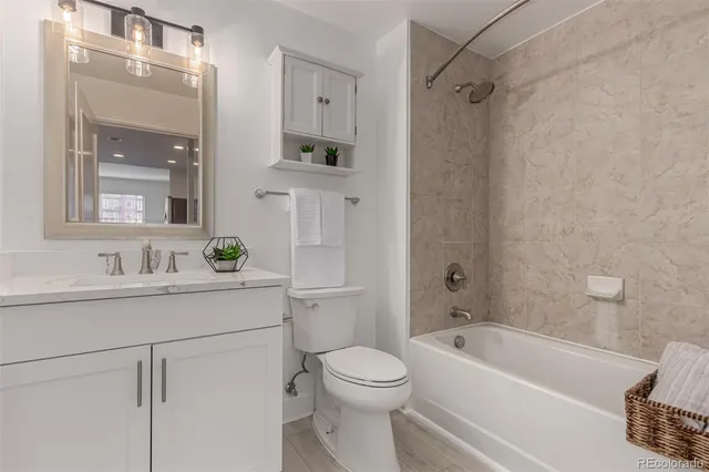 a bathroom with a toilet a sink a mirror a bathtub and vanity