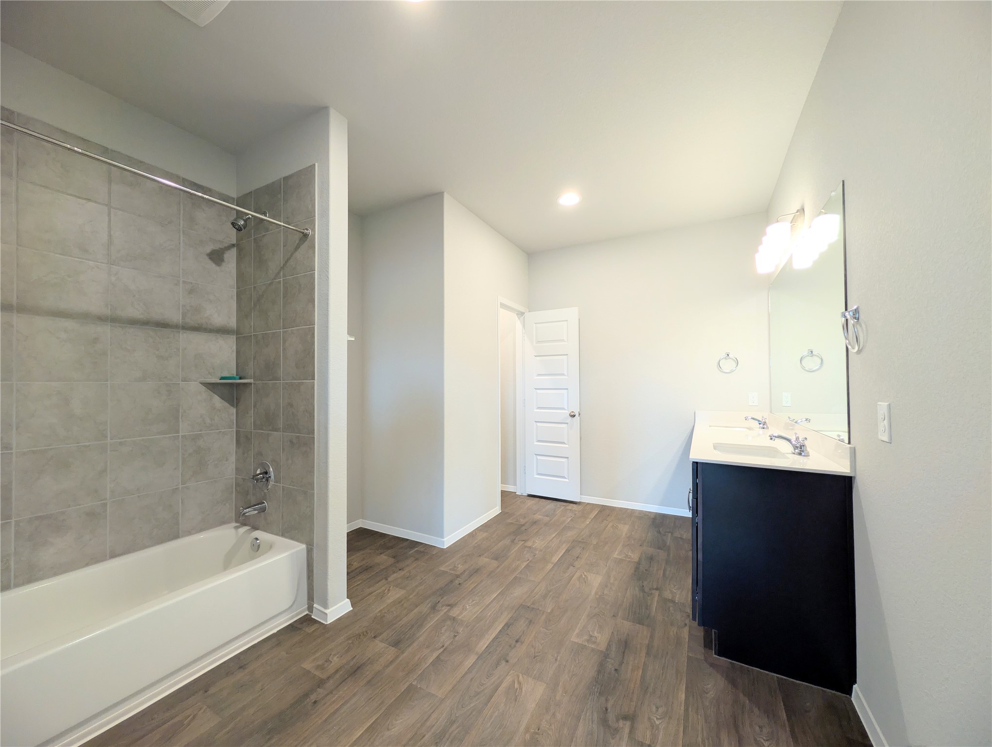 5524 Sacra Cove Austin, TX 78747 - Photo 22 of 37 Primary bathroom with vanity, dark wood finished floors, shower combination, and recessed lighting