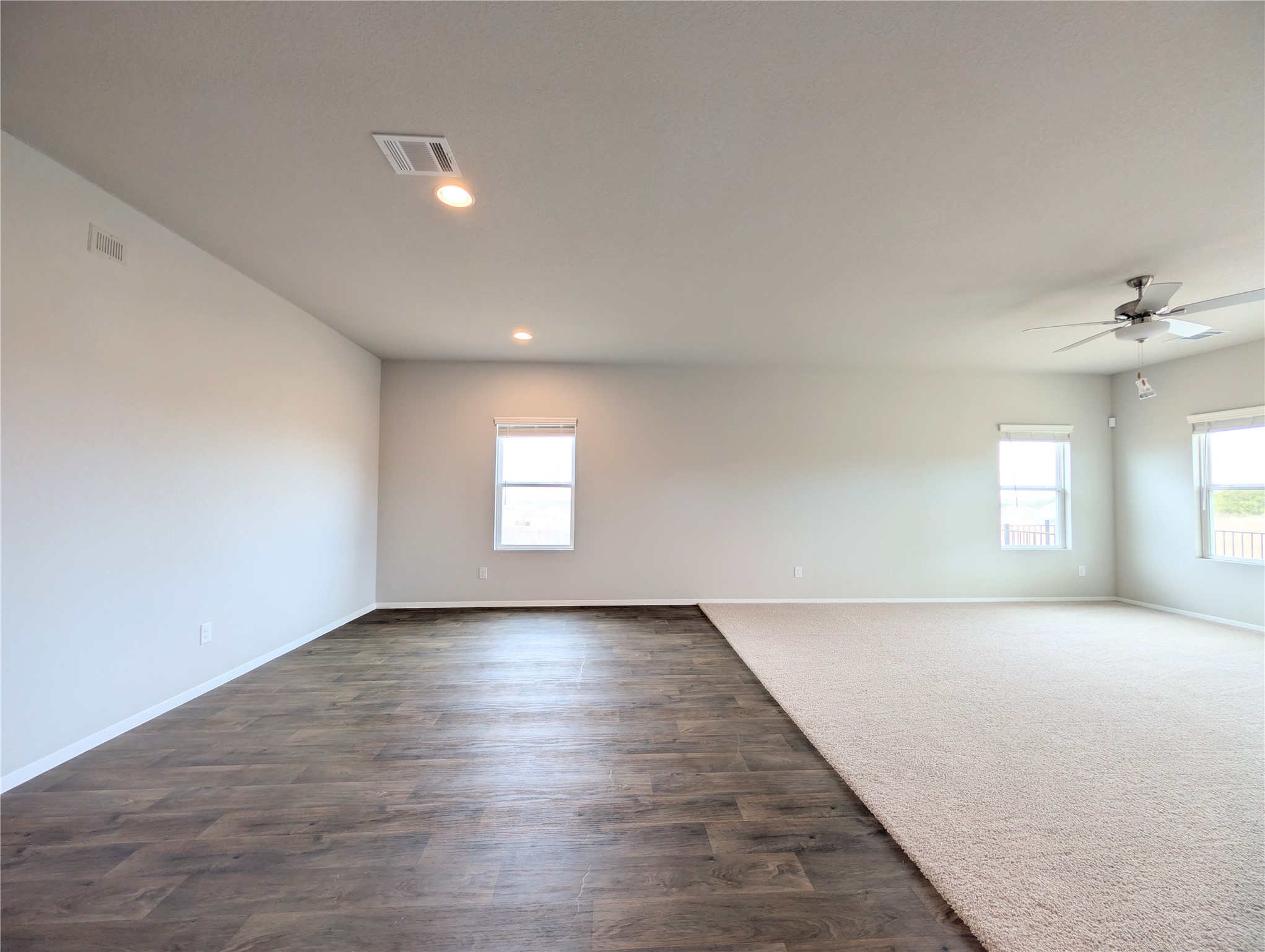 5524 Sacra Cove Austin, TX 78747 - Photo 3 of 37 Empty room featuring a ceiling fan, dark wood-type flooring, recessed lighting, and dark carpet