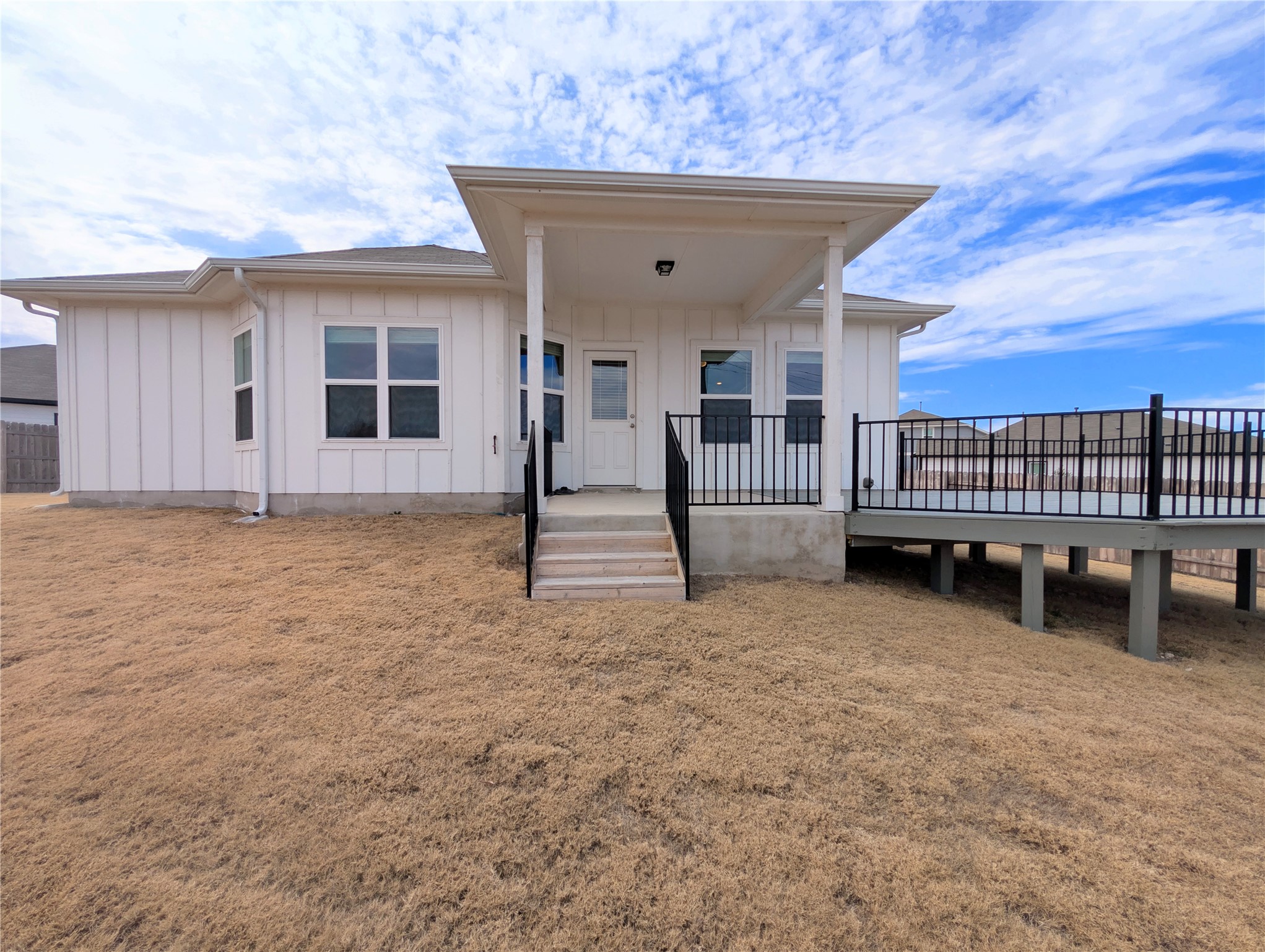5524 Sacra Cove Austin, TX 78747 - Photo 33 of 37 View of back facade featuring board and batten siding, a back lawn, and covered patio