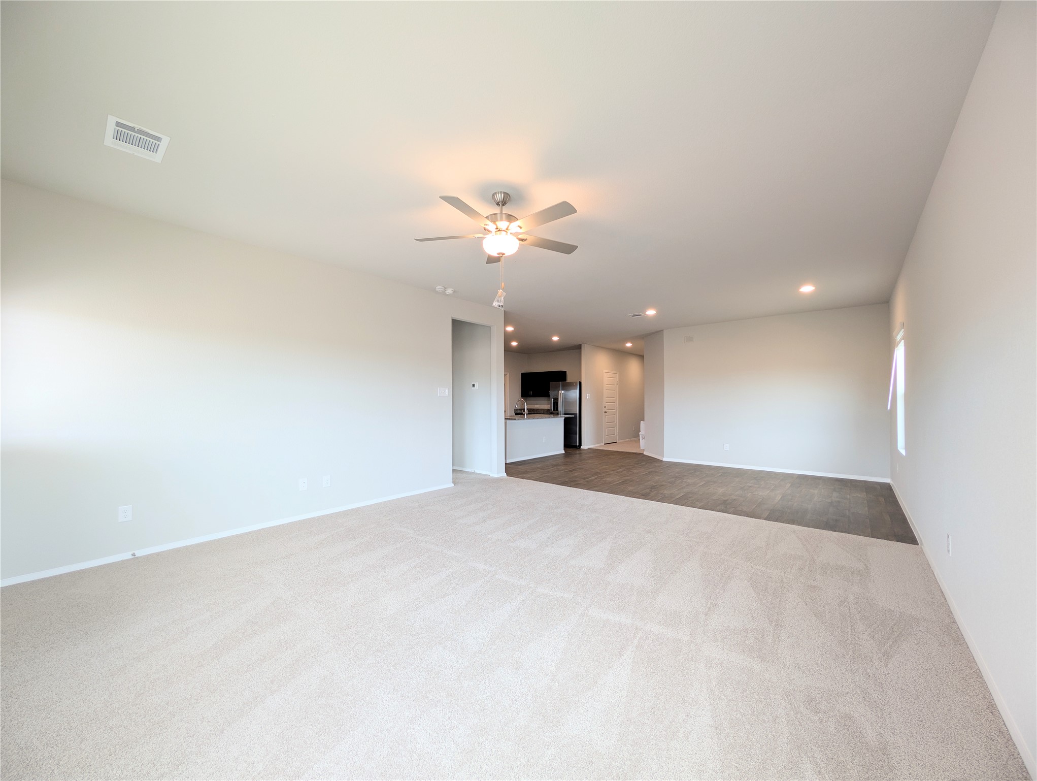 5524 Sacra Cove Austin, TX 78747 - Photo 6 of 37 Unfurnished living room with a ceiling fan, light carpet, and recessed lighting