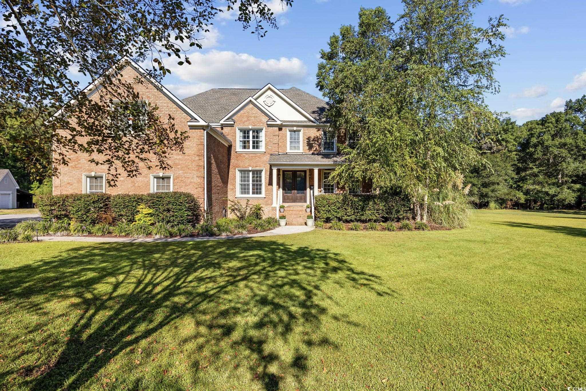 View of front of house with a front lawn, brick siding, and covered porch