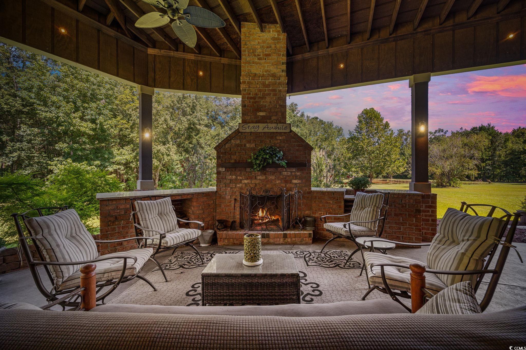 2273 Starduster Lane Little River, SC 29566 - Photo 32 of 40 Patio terrace at dusk featuring an outdoor living space with a fireplace, a ceiling fan, and a patio area