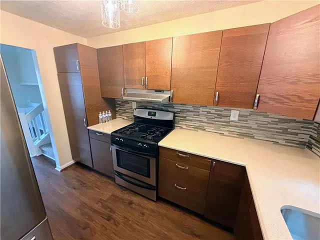 a kitchen with stainless steel appliances granite countertop a stove a sink and a refrigerator with wooden floor