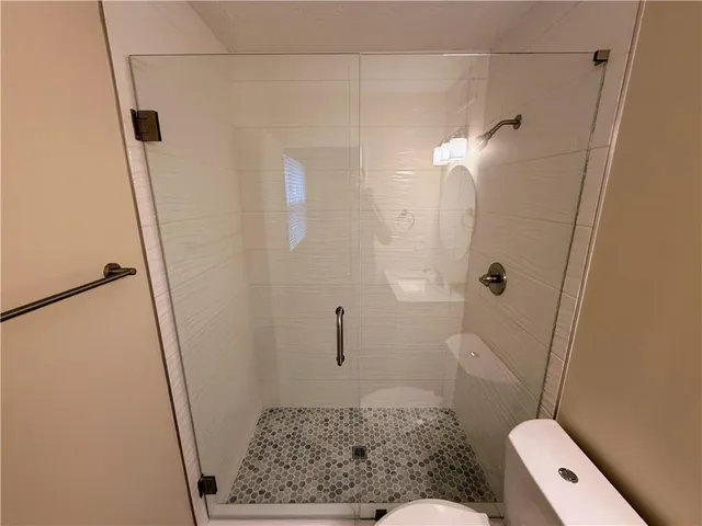 a white toilet sitting next to a shower