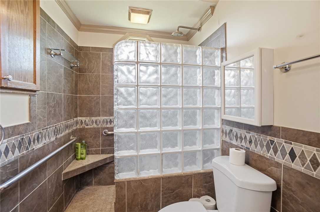 1444 Eagle City Road Springfield, OH 45504 - Photo 26 of 50 This bathroom features a glass block shower and decorative tiled walls.