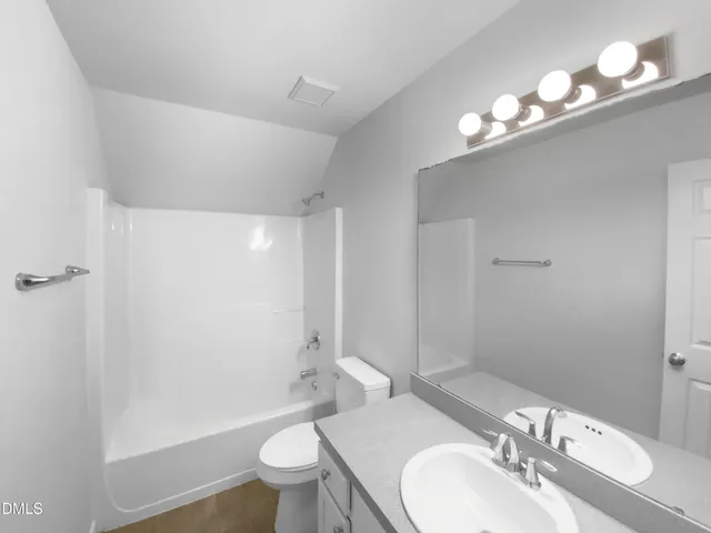 a bathroom with a sink a toilet a mirror a vanity and shower