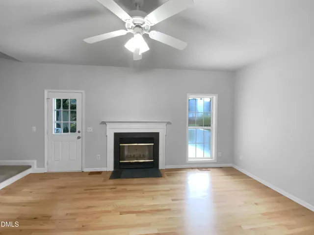 an empty room with windows and fireplace