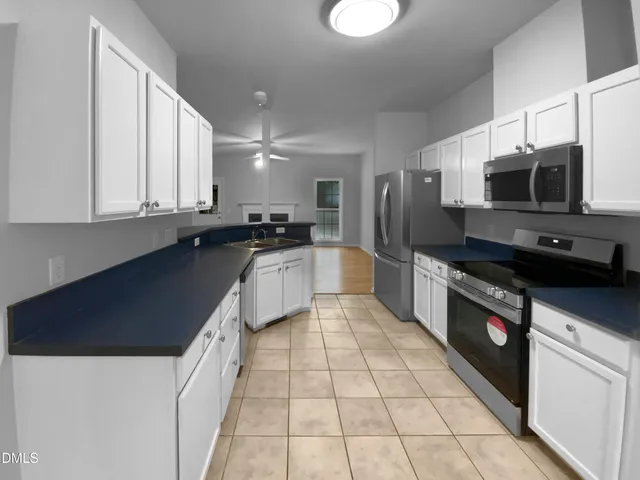 a large kitchen with a stove a sink dishwasher a microwave oven with granite countertops and cabinets