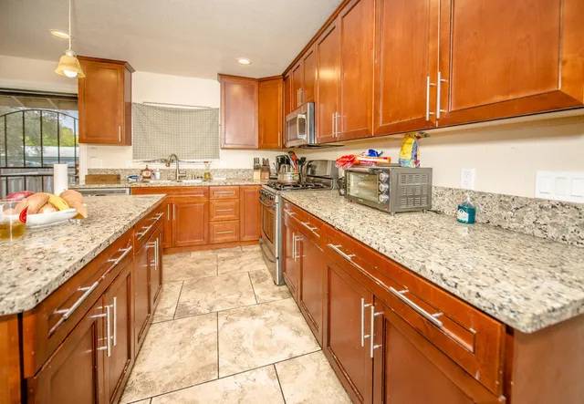 a kitchen with stainless steel appliances granite countertop a sink a stove and a refrigerator